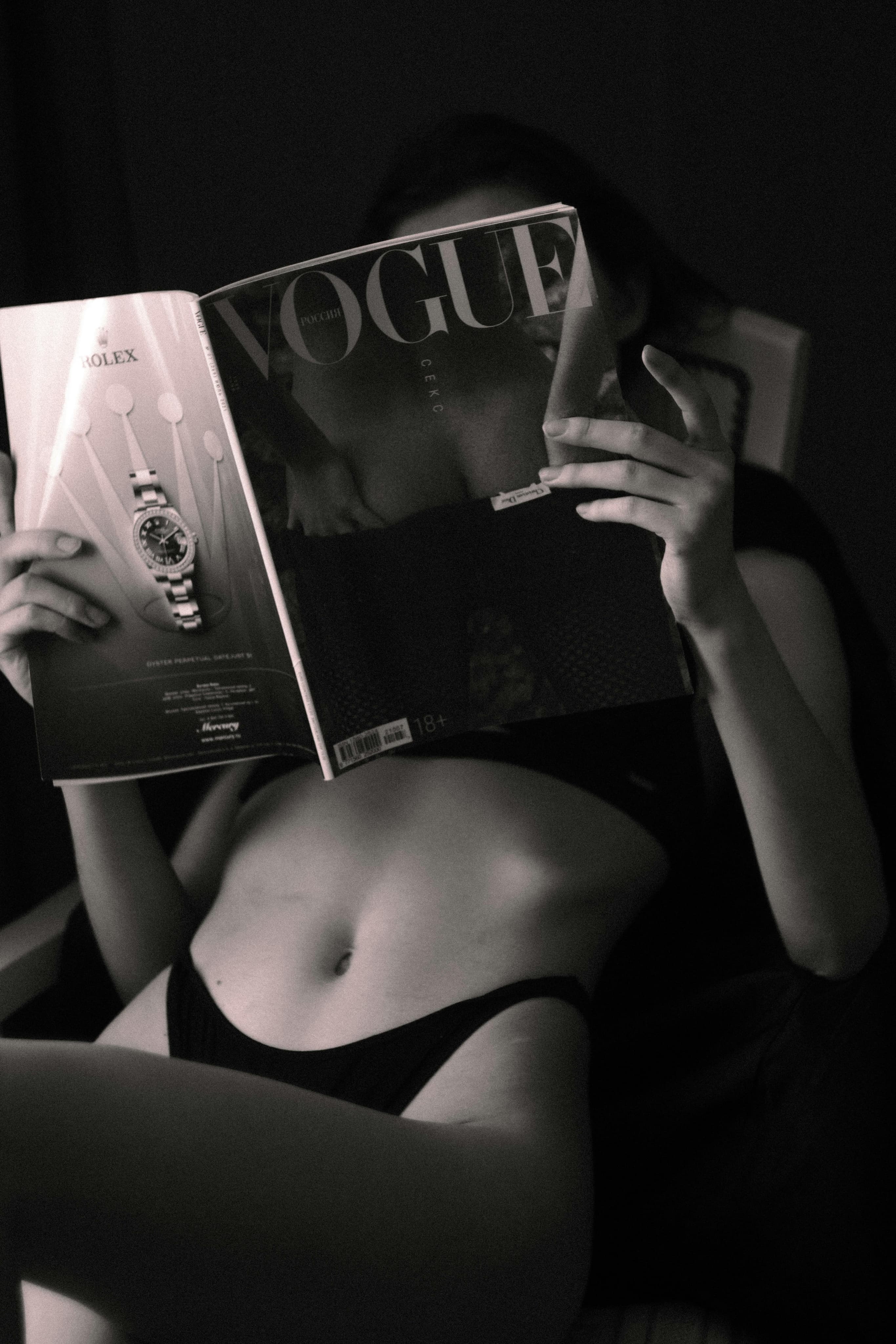 A woman wearing a swimsuit reading a magazine
